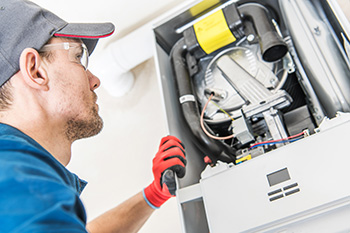 Furnace repair in Ocean County; technician looking at internal components