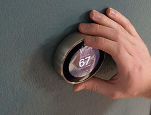 Homeowner setting smart thermostat to increase energy efficiency